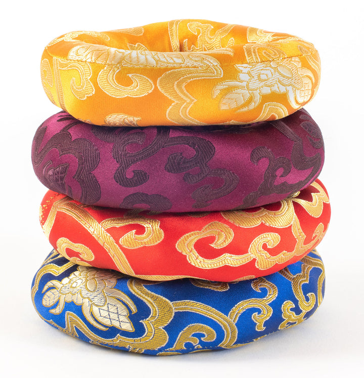 image of stacked singing bowl cushions, blue, red, purple, yellow with designs